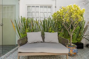 Ein Zimmer mit einer Couch, einem Blumentopf und einem Fenster.