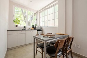 A kitchen with a dining table, chairs, a microwave, and a potted plant. - Apartamento de 1 dormitorio (Diego) (Ciudad de México)