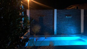 A modern outdoor pool area with a brick wall and a blue-lit water feature. - 3-bedroom house in amazing Darién with cool AC breeze (Darién)
