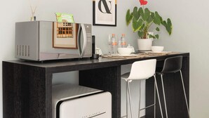 Cozinha moderna com micro-ondas, geladeira, máquina de café, uma planta em vaso e um quadro na parede.