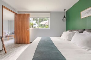 A modern bedroom with a large bed, a wooden door, a window with a view, and a green accent wall. - Loft Con Terraza (PINO) (Ciudad de México)