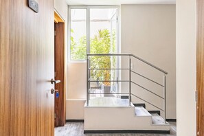 Ein modernes Interieur mit einer Holztür, einer Metalltreppe und Blick ins Grüne.