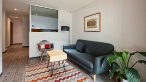 Ein modernes Wohnzimmer mit einer Couch, einem kleinen Tisch, einer Lampe und einem Blumentopf.