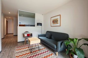 Ein modernes Wohnzimmer mit einer Couch, einem kleinen Tisch, einer Lampe und einem Blumentopf.
