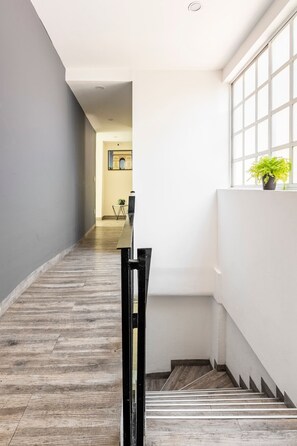 Ein Flur mit Holzboden, einer Treppe und einem Fenster mit Pflanze.