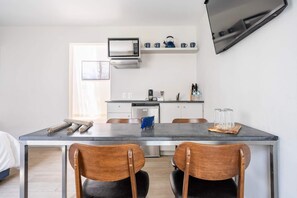 Una cocina moderna con una mesa de comedor, sillas, un microondas y una cafetera.