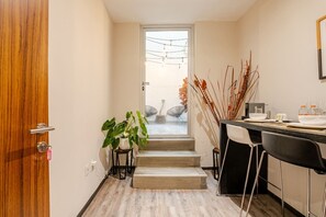 A modern kitchen with a wooden door, a staircase leading to a balcony, and a dining area with chairs and a table. - Super Loft Corazon Polanco (Abedul) (Ciudad de México)