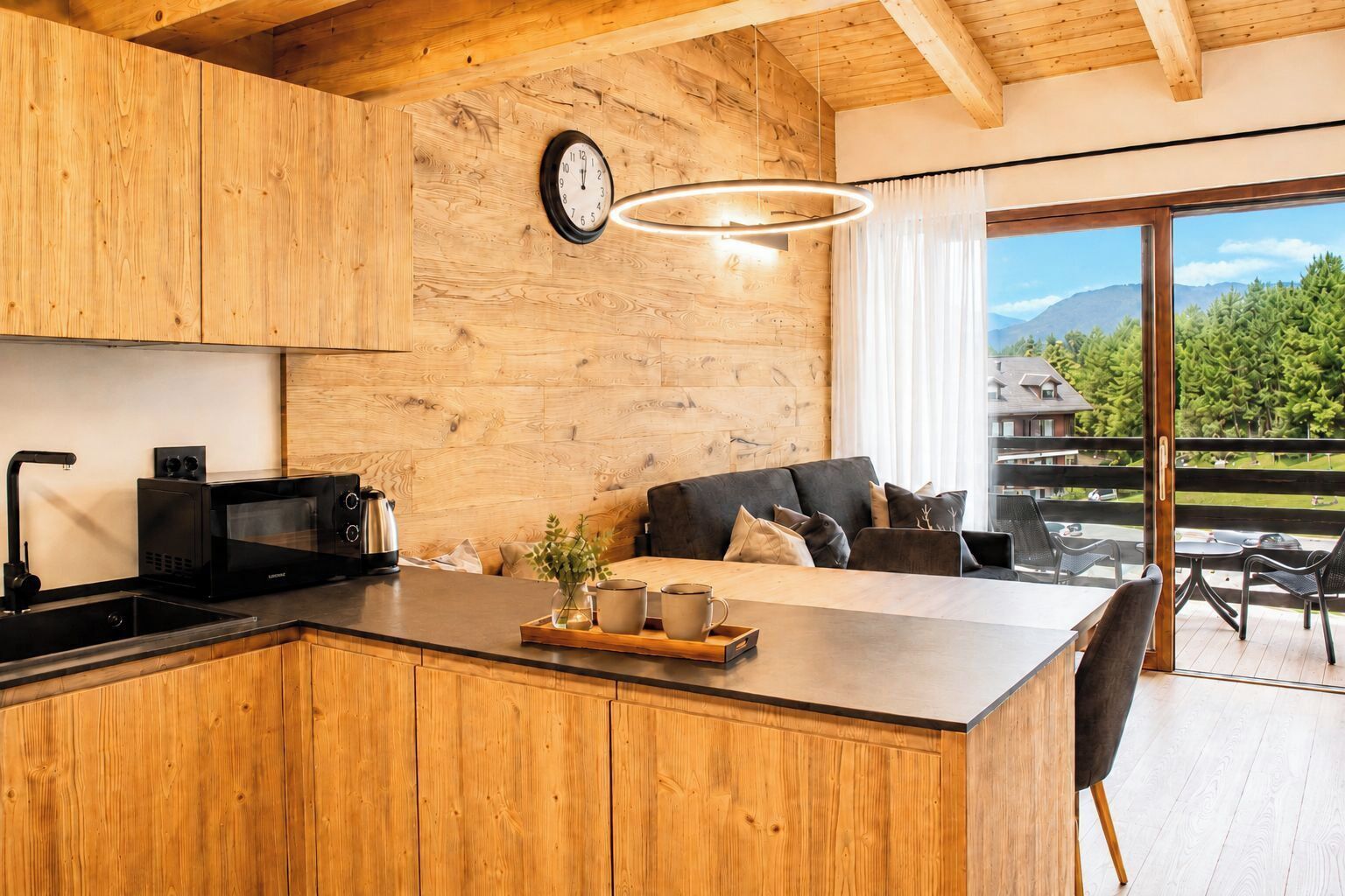 Une cuisine moderne avec des meubles en bois, un four à micro-ondes encastré et un grand îlot central doté de sièges.