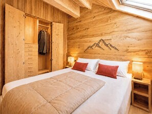 Una habitación de madera con una cama, un armario y una lámpara fijada a la pared.
