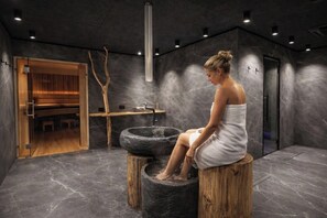 Un cuarto de spa con una pila de piedra, taburetes de madera y un armario de madera.