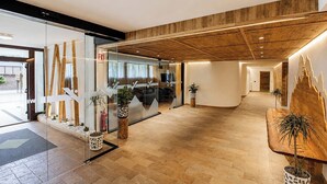 A modern hotel lobby with a wooden ceiling, glass partitions, and potted plants. - Lucky Fox Loft - Residence Veronza (Cavalese)