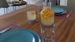 Een eettafel met blauwe borden, een karaf met fruitsap en een glas water.