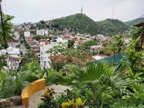 A residential area with buildings, greenery, and a hill in the background. - Beautiful apartment with a view of the small town and just 10 minutes from the Romantic District. (Puerto Vallarta)