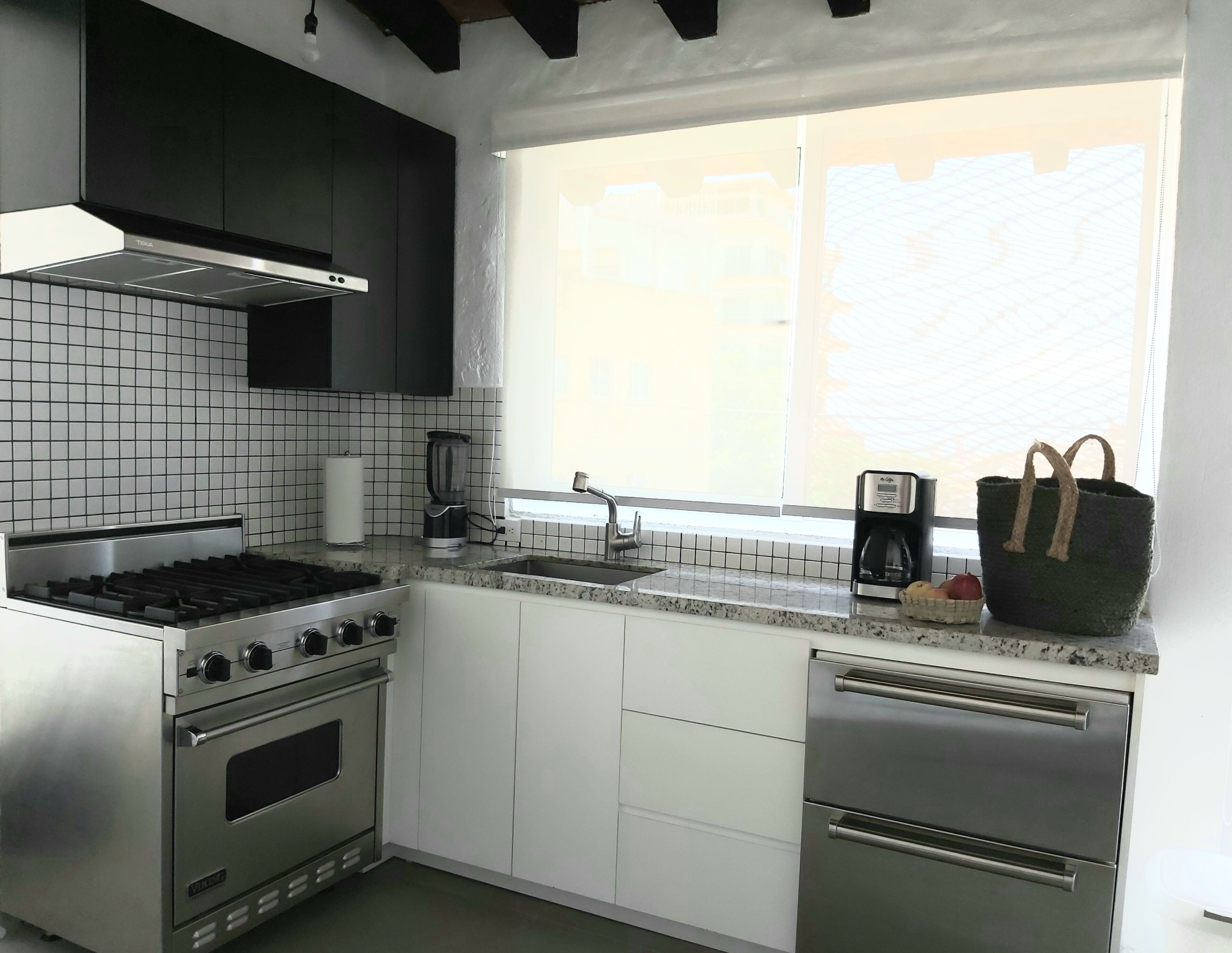 A modern kitchen with a gas stove, oven, dishwasher, and a window with a view.