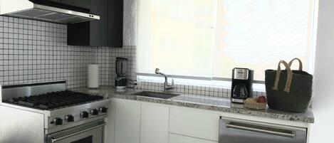 A modern kitchen with a gas stove, oven, dishwasher, and a window with a view.