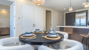 A modern dining area with a round table set for four, surrounded by white chairs. - Luxury beach front condo Viento 303 (Puerto Peñasco)