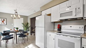 A modern kitchen with white cabinetry, a built-in microwave, a stove, and a dining area with a table and chairs. - Family Friendly* Firepit * Dogs OK * Fenced Yard (Savannah)