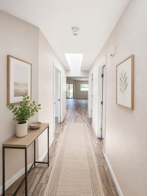 A hallway with a skylight, framed artwork, a potted plant, and a wooden console table. - Charming 2-bedroom townhome in Punta Gorda perfect for relaxing stay (Punta Gorda)