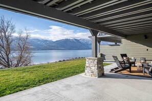 A covered patio with a view of a lake and mountains, stone pillar, and outdoor furniture. - Luxury Lakefront Condo C1 + BBQ in Wapato Chelan (Manson)