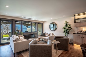 A modern living room with a sofa, armchairs, a coffee table, and a view through large windows. - Luxury Lakefront Condo C1 + BBQ in Wapato Chelan (Manson)