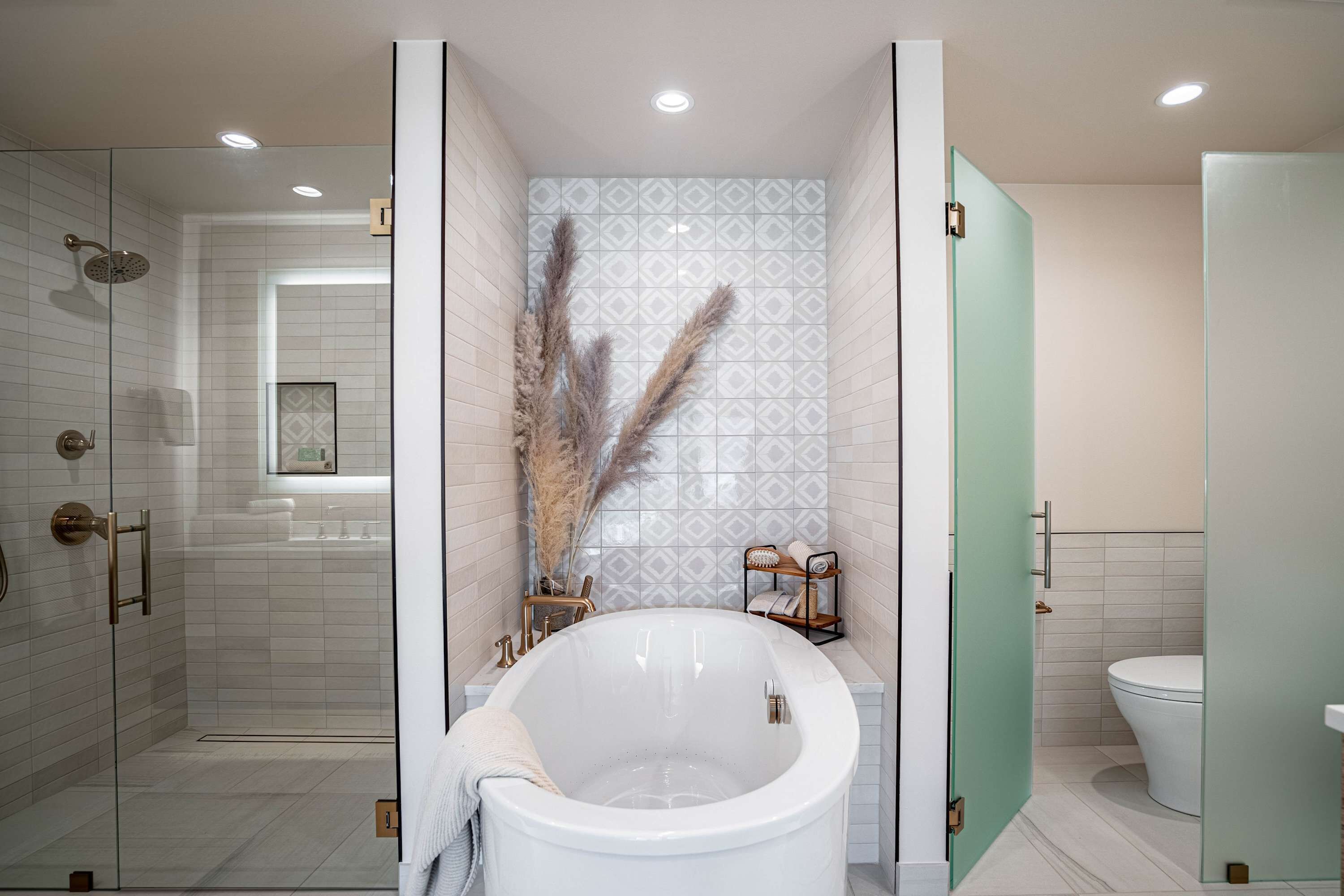 Een moderne badkamer met een vrijstaand bad, een glazen douchecabine en een toilet.