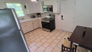 A compact kitchen with a refrigerator, microwave, oven, and sink. - Spacious 3BR Home Near Fort Moore Sleeps 6 Full Kitchen (Columbus)