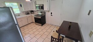 A compact kitchen with a refrigerator, microwave, oven, and sink. - Spacious 3BR Home Near Fort Moore Sleeps 6 Full Kitchen (Columbus)