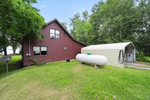 A red house with a white garage and a green lawn. - Doc's Place on Lark's:  Sleeps 4-Kayaks-Lakefront! (Pellston)