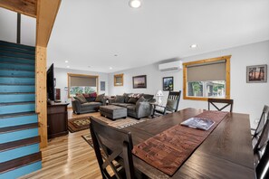 Amplia sala de estar con mesa de comedor de madera, varios sofás y una escalera con escalones azules.