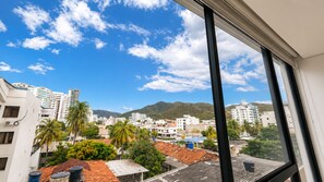 Un paisaje urbano con edificios, palmeras y montañas al fondo.