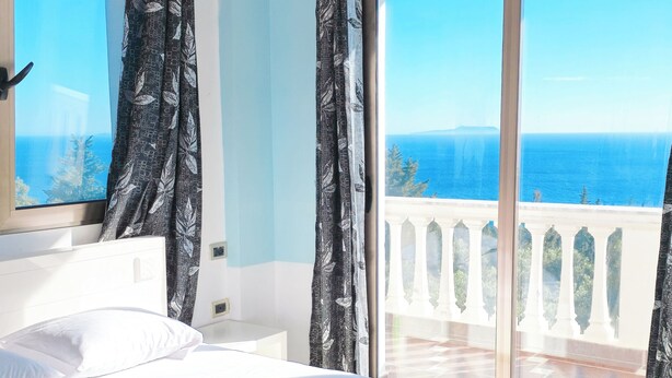 Un dormitorio con cama, cortinas y balcón con vistas.