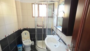 Un baño con inodoro, cabina de ducha y lavamanos.