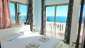 Habitación de hotel con cama, dos toallas, una ventana y vista al mar.