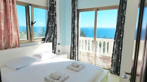 Habitación de hotel con cama, dos toallas, una ventana y vista al mar.