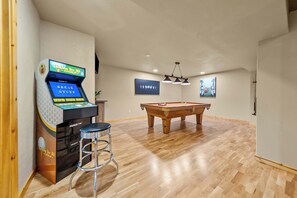 Ein Zimmer mit Poolbillardtisch, Barhocker und einer 3D-Golf-Spielhalle.