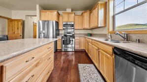 Una cucina moderna con mobili in legno, elettrodomestici in acciaio inossidabile e un'ampia finestra.