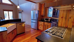 A kitchen with wooden cabinets, a built-in stove, a refrigerator, and a microwave. - Serene 4-bedroom house in Seeley Lake perfect for relaxing stays (Seeley Lake)