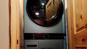 A compact washer and dryer unit with a control panel, housed in a wooden cabinet. - Serene 4-bedroom house in Seeley Lake perfect for relaxing stays (Seeley Lake)