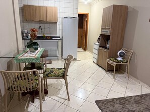 Cozinha compacta com área de refeições, incluindo mesa, cadeiras, geladeira e armários.