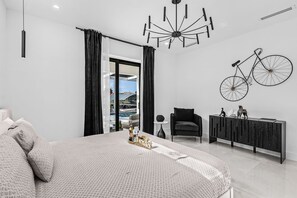 Ein modernes Schlafzimmer mit einem großen Bett, einem schwarzen Sessel, einem Konsolentisch und einer Fahrrad-Wanddekoration.