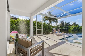 Ein Außenpoolbereich mit Liegestühlen und einem Whirlpool, umgeben von einer überdachten Terrasse mit Blick auf einen See und viel Grün.
