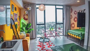 A modern room with a large window, a green bed, a dining table, and a sofa.