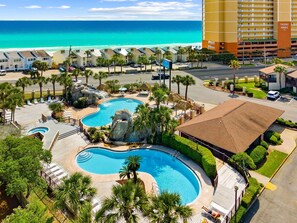 Ein Hotel mit Poolbereich, Blick auf den Strand und einem Parkplatz.