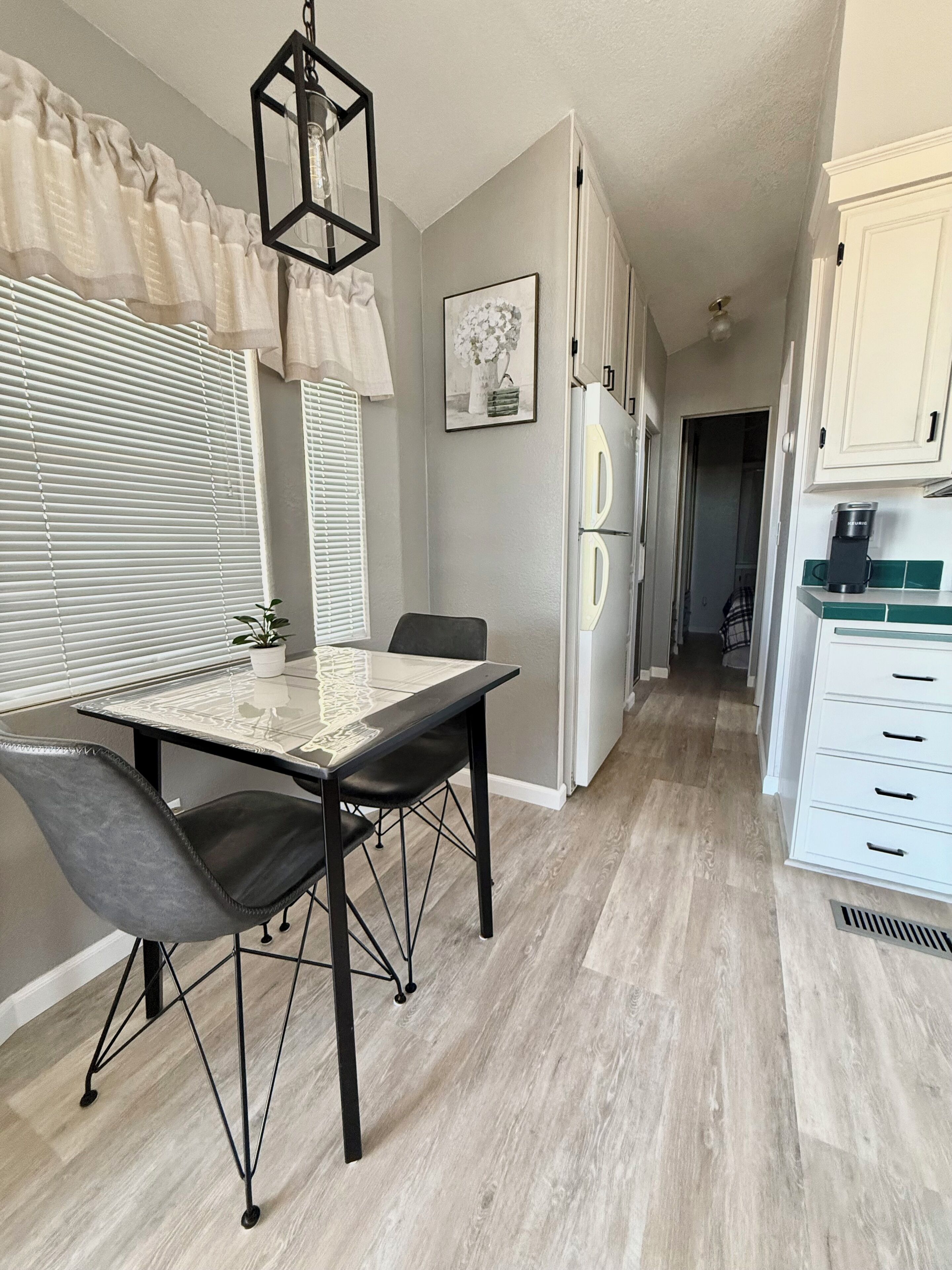 A modern kitchen with a dining table, chairs, and a refrigerator.