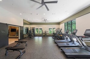 Ein Fitnessstudio mit Laufbändern, Kraftgeräten und einer Spiegelwand.