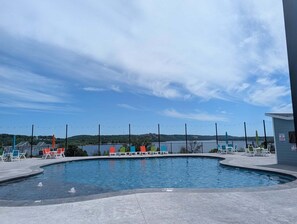 Una piscina con sillas de descanso y vistas a un lago y colinas.