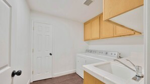 A laundry room with a washing machine, dryer, and sink.