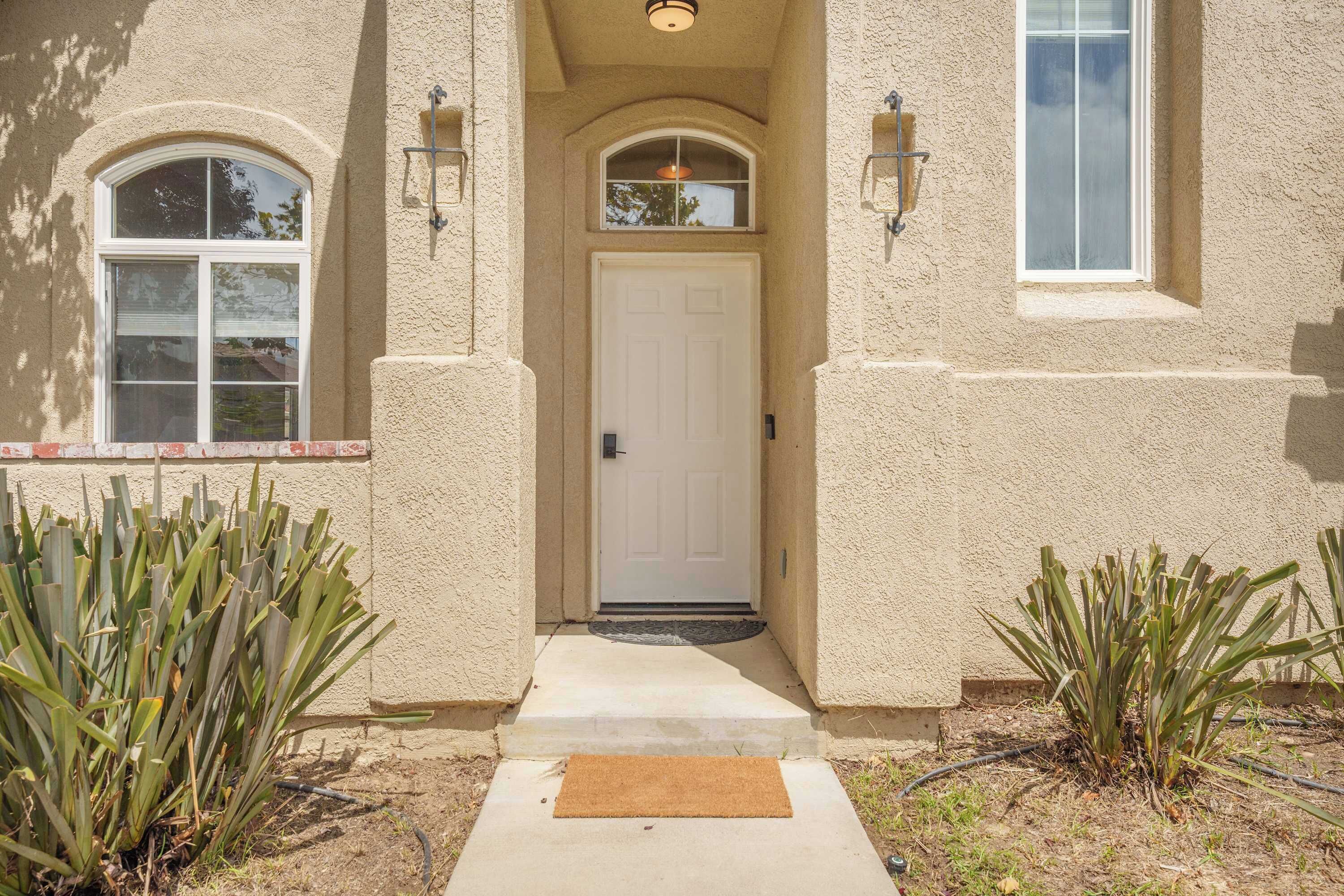 A house entrance with a white door, two windows, and a small porch area.