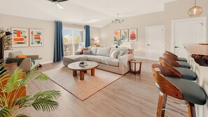 Een moderne woonkamer met een bank, salontafel en barstoelen.