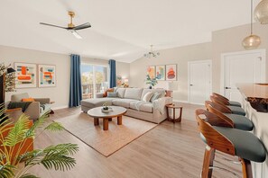 A modern living room with a sofa, coffee table, and bar stools. - The King & Bear Retreat (St. Augustine)